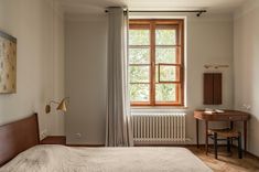 a bed sitting under a window next to a wooden desk