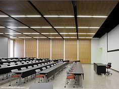 an empty classroom with rows of desks and chairs in front of a projector screen