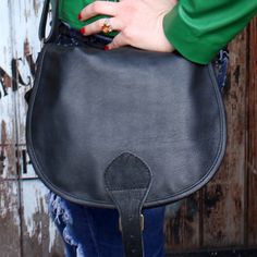 Our black leather Isabelle saddle bag is a perfectly made saddle-bag based on a real 70's pattern with pocket under flap.  The front pocket is very useful and helps to keep your items separate and secure.  The lining is waterproof with a built-in pocket.  The Isabelle medium bag is 9cms or 3.5 inches deep, 26cms or 11.4 inches wide, 25cms or 9.8 inches in length, and the handle extends to 135cms or 53.1 inches and is 3cms or 1.1 inches thick.A very useful spacious bag. The bag of the decade in the 70's, you can't go wrong with this one Black leather may vary from the picture, please check, we are always here 70's Pattern, Saddle Purse, Black Saddle Bag, Free Post, Saddle Bag, Messenger Bags, Medium Bags, Saddle Bags, Classic Black