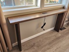 a long wooden table sitting next to a window with a phone plugged into it