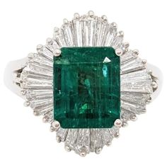 an emerald and diamond ring with baguets on the shoulders, set in white gold