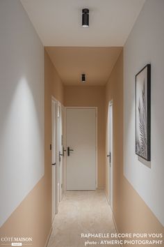 an empty hallway with two white doors leading to another room that has beige walls and tan flooring