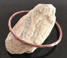 a close up of a rock on a table with a metal bracelet attached to it