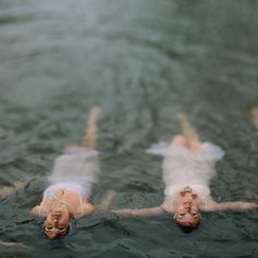 three people floating in the water on their stomachs and legs, with one person laying down