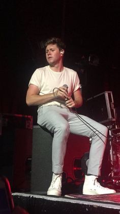 a man sitting on top of a stage holding a microphone