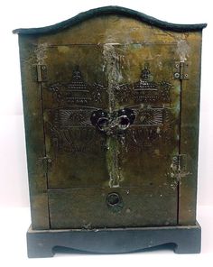 an old metal box with carvings on the front and sides, sitting against a white background