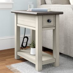 a small end table with a plant on it in front of a couch and chair