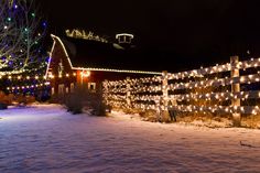 a fence covered in christmas lights next to a house