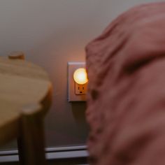 a light that is on in the corner of a room next to a wooden table