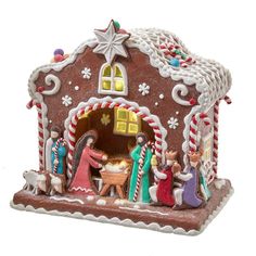 a gingerbread house decorated with figurines and candy canes for the nativity