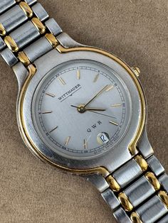 Discover a fabulous vintage Swiss-made Wittnauer dress watch, featuring gold and stainless steel in a two-tone design. The original 7.75-inch band includes extra links and a Wittnauer buckle. The watch showcases a 1.25-inch case adorned with Roman numerals, gold hands, and raised markers, with a date display at 6 o'clock. Crafted in the mid-1980s, it boasts a 1.25-inch case with 10-micron 18K gold plating, a silver dial, and a high-quality 7-jewel Swiss movement. The dial is marked GC2515 Swiss 9552. This timepiece has been serviced, cleaned, sanitized, and fitted with a new battery, ensuring it is fully reconditioned. with box and instructions Dress Watch, Gold Hands, Wristwatch Men, Swiss Made, Roman Numerals, Wrist Watches, O Clock, Gold Plating, Time Piece