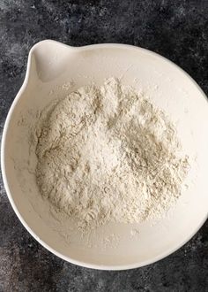 a white bowl filled with flour on top of a table