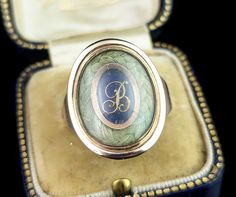 This beautiful antique Georgian era, late 18th century mourning ring is truly a beautifully crafted piece. It features a beautiful large oval face housing a lock of plaited dark blonde hair bordering a cobalt blue enamel plaque with applied rose gold lettering with the initial B. The slightly domed glazing encloses this and is original to the ring, the reverse of the face has a closed back setting and is engraved with an inscription for the departed; William Bridge, Ob 4th Mar 1797 Ae 81. The ring has chunky gold shoulders, yellow gold with warm rosey tones and a closed back setting.  It comes in an antique leather bound ring box.  A true beauty, this would be a fantastic gift for the collector of mourning jewellery or as a gift to yourself. Dated 18th century Georgian pieces are always in Victorian Hallmarked Oval Enamel Ring, Victorian Oval Hallmarked Enamel Ring, Antique Engraved Yellow Gold Enamel Ring, Victorian Oval Enamel Ring For Anniversary, Antique Oval Enamel Ring Collectible, Vintage Oval Engraved Ring With Initials, Victorian Gold Enamel Oval Ring, Victorian Gold Oval Enamel Ring, Victorian Style Gold Enamel Oval Ring