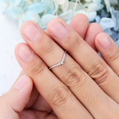 a woman's hand with a diamond ring on top of her finger, next to a bouquet of flowers