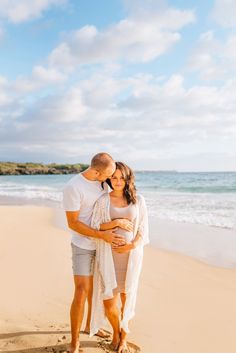 a pregnant couple embracing on the beach