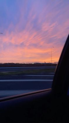 the sun is setting over an airport with clouds in the sky and cars on the road