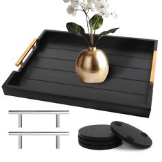 there is a tray with flowers in it and two black plates on the table next to it