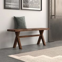 a wooden bench sitting on top of a cement floor next to a wall with pictures above it