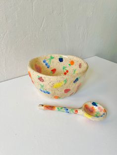 a bowl and spoon sitting on top of a white table next to a painted wall