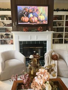 a living room filled with furniture and a fire place covered in pumpkins on the mantle