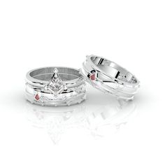 two white gold wedding rings with red stones on each side and a princess cut diamond in the middle