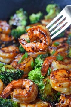 shrimp and broccoli being cooked in a skillet with a fork stuck into it