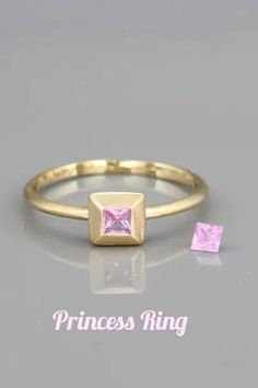 a princess ring with pink cubics on the side and gold plated, in front of