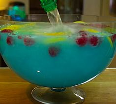 a glass filled with blue liquid and topped with raspberries