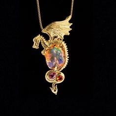 "Luminiferous Dragon soars into our one of a kind collection clutching a 10.5 carat Mexican fire opal. The stunning opal has been expertly sculpted to expose maximum play of color. Lavender, green and orange radiate from within. This precious opal is 6/8\" long x 5/8\" across. (19mm x 15mm) Luminiferous Dragon is lost wax cast in 18K gold. Luminiferous Dragon is detailed and three dimensional. A 4mm x 6mm pink sapphire and a 4mm x 6 Mexican Fire opal are set in the curves of the dragon's tail. I Opal Dragon, Mexican Fire Opal, Precious Opal, Lavender Green, Gold Dragon, Dragon Necklace, Dragon Jewelry, Dragon Pendant, Lost Wax