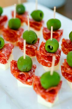 small appetizers with green olives and prosciutto on a white plate