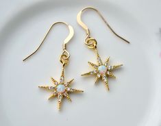 A perfect treat for someone special - maybe yourself! - which will brighten up the cooler days and nights ahead with subtle sparkle and evergreen style, these dainty star earrings will arrive ready to gift. The 8-pointed gold star earrings have sweet star charms studded with tiny cubic zirconia stones and with a central opal effect stone that reflects beautiful rainbow hues. Suspended on high quality gold fill hooks. The star charms are made of brass, with eight pointed rays radiating out from t Star-shaped Jewelry With Sparkling Stones For Gift, Star-shaped Jewelry With Sparkling Stones As A Gift, Star-shaped Sparkling Stones Jewelry For Gifts, Star-shaped Sparkling Jewelry As Gift, Starburst Cubic Zirconia Jewelry Gift, Gold Plated Sparkling Earrings For Gift, Sparkling Gold-plated Earrings For Gift, Festive Jewellery, Gold Star Earrings