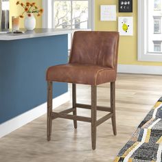 a brown leather bar stool sitting on top of a hard wood floor next to a kitchen counter