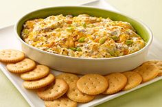 a casserole with cheese and crackers on a plate next to some crackers