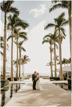 a bride and groom standing in front of palm trees at their wedding venue on the beach