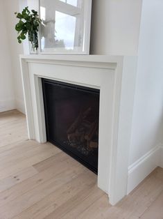 a white fireplace with a potted plant on top