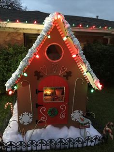 a gingerbread house is decorated with lights and candy canes for the holiday season