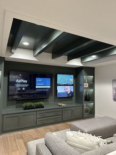 a living room filled with furniture and two flat screen tvs mounted on the wall