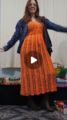 a woman wearing an orange crochet dress with her arms out in the air