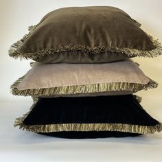 three pillows stacked on top of each other with fringe trimmings and tasseled edges