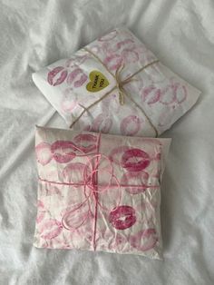 two pillows are wrapped in pink paper and tied with twine on a white sheet