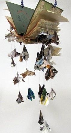 an open book is suspended from the ceiling with origami birds hanging from it