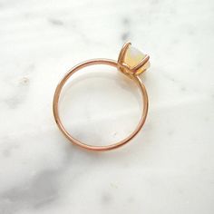 a close up of a ring on a marble surface with a gold band and an opal stone in the middle