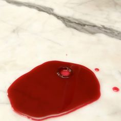 a red object sitting on top of a white marble counter next to a bottle of wine