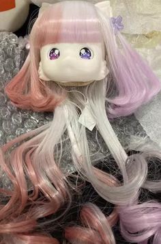 a doll with pink and purple hair laying on top of some silver rocks next to a stuffed animal