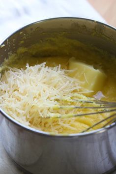 a metal bowl filled with cheese and grated cheese