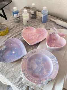 three heart shaped plates sitting on top of a table next to paint bottles and other items