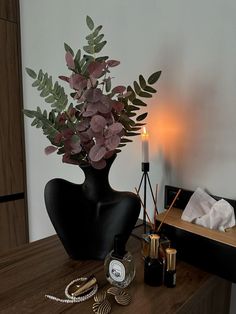 a black vase filled with flowers on top of a wooden table next to a mirror