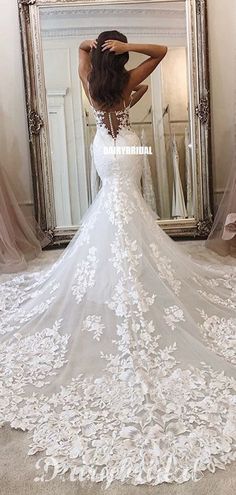 a woman is standing in front of a mirror wearing a wedding dress