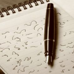 a pen sitting on top of a spiral notebook next to an empty notepad with writing