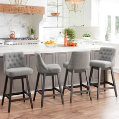 three gray chairs are sitting in front of an island with marble countertops and white cabinets